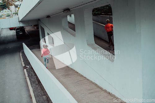 Image of Two women in sports clothes running in a modern urban environment. The concept of a sporty and healthy lifestyle