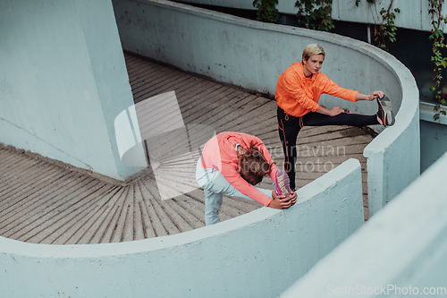 Image of Two women warming up together and preparing for a morning run in an urban environment. Selective focus