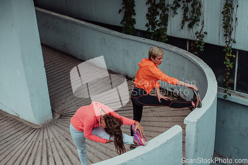 Image of Two women warming up together and preparing for a morning run in an urban environment. Selective focus