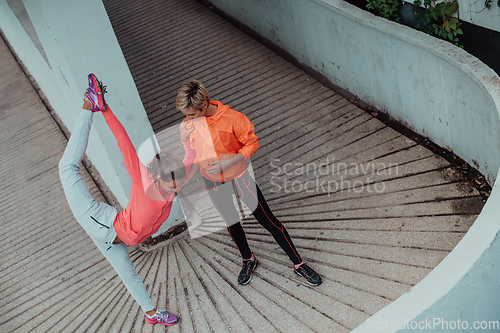 Image of Two women warming up together and preparing for a morning run in an urban environment. Selective focus