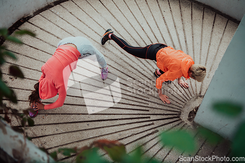 Image of Two women warming up together and preparing for a morning run in an urban environment. Selective focus