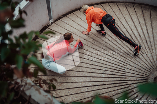 Image of Two women warming up together and preparing for a morning run in an urban environment. Selective focus