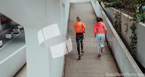 Image of Two women in sports clothes running in a modern urban environment. The concept of a sporty and healthy lifestyle