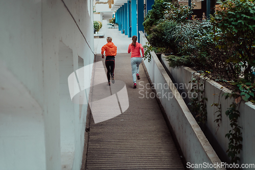 Image of Two women in sports clothes running in a modern urban environment. The concept of a sporty and healthy lifestyle