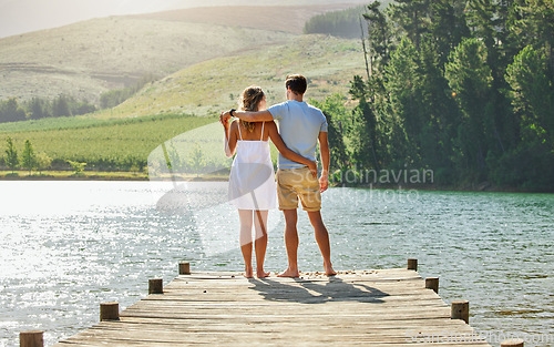 Image of Couple on jetty by the lake, travel and relax together with nature and hug outdoor, love with care and bonding. Summer, holiday with man and woman back view, sunshine and relationship with trust