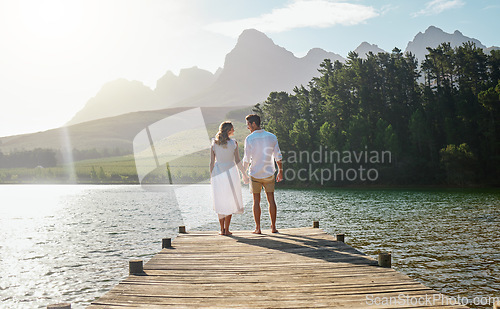 Image of Love, couple and holding hands at lake, smile and bonding outdoors on vacation sunrise. Romance date, care and happy man and woman with trust, support or affection for romantic holiday at creek pier