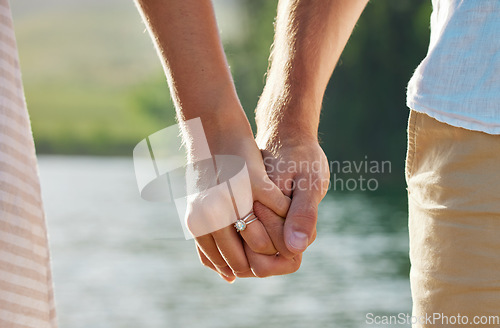 Image of Holding hands, engagement and couple at lake outdoors for love, trust and support. Commitment, care and ring jewelry of woman and man together for romance, bonding or affection with soulmate at creek