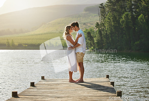 Image of Couple, lake and engagement announcement of young people in love in nature. Happy, relax and hug of a woman and man together by water outdoor on summer vacation by a lakeside on holiday break