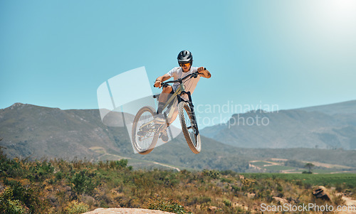 Image of Mountain bike, cycle and air with a sports man jumping outdoor while riding on a track for adrenaline. Fitness, sky and risk with a male athlete taking a ride on his bicycle for freedom or adventure