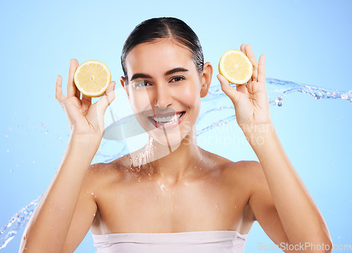 Image of Health, lemon and water splash with portrait of woman in studio for natural cosmetics, nutrition and detox. Glow, fruits and hydration with female on blue background for diet, clean face and skincare