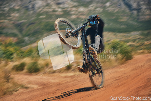 Image of Cycling, training and person on a bicycle in the countryside for extreme sport, adrenaline and fun. Speed, action and cyclist on a dirt road for stunt, trick or fitness, freedom and balance in nature