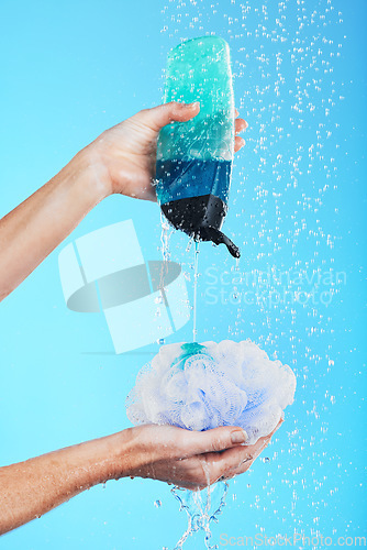 Image of Skincare, dermatology and hands with loofah and shower gel of person washing isolated in a studio blue background. Self care, beauty and person or model using soap and sponge for morning routine