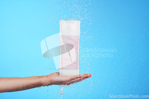 Image of Shampoo, showing and hand with a bottle in the shower isolated on a blue background in studio. Cleaning, hygiene and person advertising a product for grooming, sanitary care and treatment with mockup