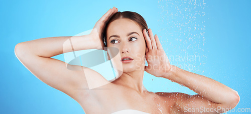 Image of Shower, water and woman washing in studio for skincare, wellness and clean body for self care. Face of female aesthetic model, splash or drops for cleaning, hygiene and cosmetics on blue background