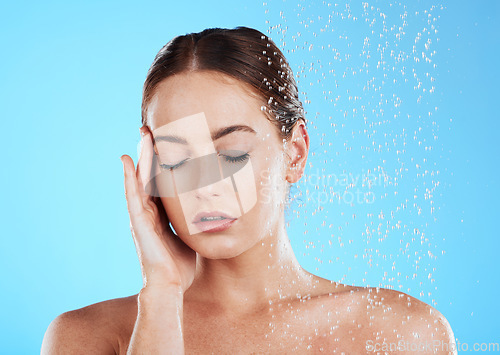 Image of Shower, water and relax woman in a studio feeling happy from cleaning and skincare. Wellness, splash and beauty routine of a female model excited from dermatology and self care with blue background