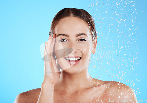 Image of Shower, water and portrait of happy woman in a studio face from cleaning and skincare. Wellness, splash and beauty routine of female model excited from dermatology and self care with blue background