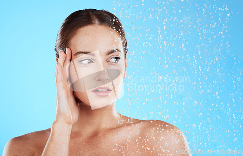 Image of Shower, water and woman thinking in a studio feeling relax from cleaning or natural skincare. Wellness, wet or beauty routine of female model with facial dermatology and self care on blue background