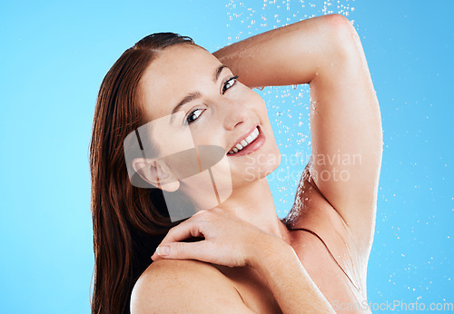 Image of Water, shower and woman washing portrait in studio for skincare, wellness and clean body for self care. Happy female model face, splash or drops for cleaning, hygiene and cosmetics on blue background