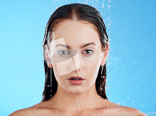 Image of Shower, water and woman portrait in a studio with calm from cleaning and skincare. Wellness, face and beauty routine of female model in bathroom for dermatology and self care with blue background