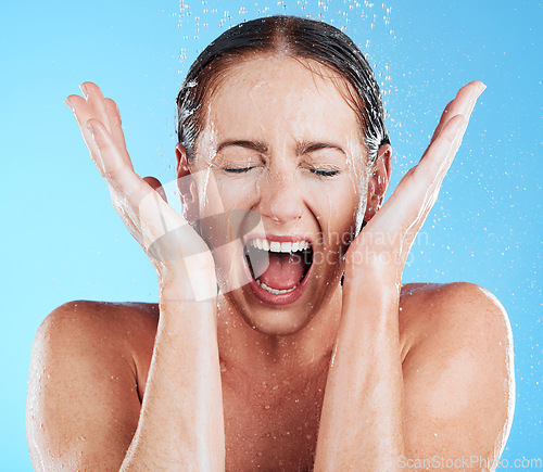 Image of Shower, water and excited woman in a studio feeling happy from cleaning and skincare. Wellness, splash and beauty routine of model screaming with facial dermatology and self care with blue background