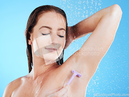 Image of Woman in shower, grooming and shaving armpit, hygiene and water drops with razor and clean on blue background. Skincare, hydration and hair removal with female cleaning body, eyes closed and calm