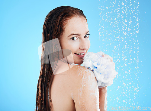 Image of Woman in shower, portrait with sponge and soap, hygiene and water drops with skincare on blue background. Washing, grooming and beauty care for happy female cleaning body, foam and mockup in studio