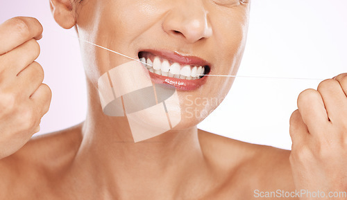 Image of Face, smile and woman flossing teeth for cleaning, hygiene or tooth care in studio isolated on a purple background. Oral health, cosmetics and happy mature female model with dental floss for wellness