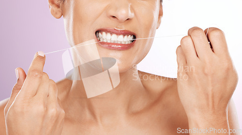 Image of Face, woman and flossing teeth for cleaning, hygiene or tooth care in studio isolated on a purple background. Oral health, fresh breath or mature female model with dental floss or thread for wellness