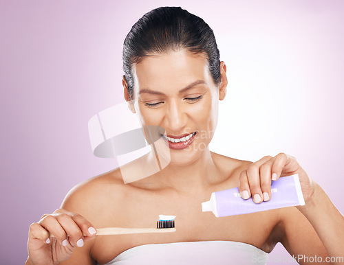 Image of Smile, woman and bamboo toothbrush and toothpaste in studio isolated on a purple background. Eco friendly, cleaning and happy mature female brushing teeth with natural wood brush for dental hygiene.