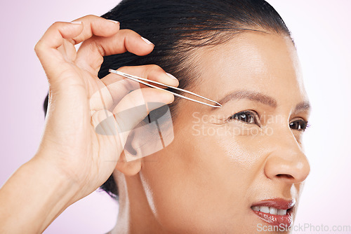 Image of Beauty, wellness and woman with tweezers in studio for mature facial hair removal routine. Self care, grooming and female model plucking her eyebrows for face epilation treatment by a pink background