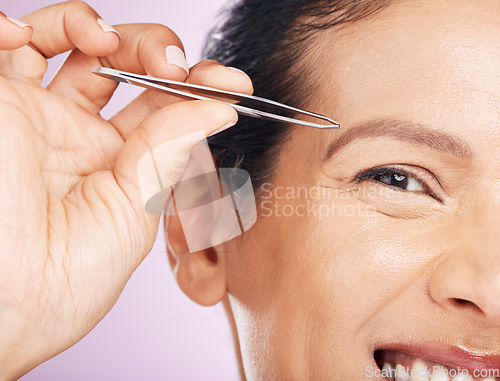Image of Woman with tweezers for plucking eyebrows in studio for mature facial hair removal routine. Self care, grooming and closeup of female model tweezing for face epilation treatment by purple background.