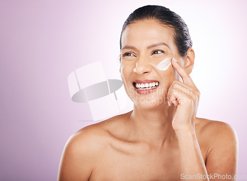 Image of Face smile, cream and skincare of woman in studio isolated on a purple background. Mature, thinking and happy female model apply dermatology lotion, creme and moisturizer cosmetics for healthy skin.