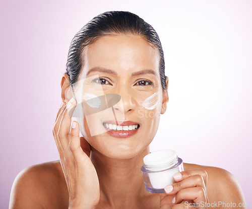 Image of Face, cream jar and skincare of woman in studio isolated on a purple background. Mature, portrait and happy female apply dermatology lotion, creme product and moisturizer cosmetics for healthy skin.