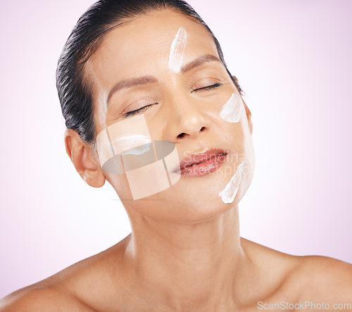 Image of Face, cream and skincare of woman with eyes closed in studio isolated on a purple background. Mature, cosmetics and serious female model with dermatology lotion, creme or moisturizer for healthy skin