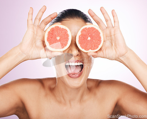 Image of Face laughing, grapefruit and skincare of woman in studio isolated on a purple background. Natural cosmetics, food and happy mature female model with fruit for vitamin c, nutrition and healthy diet.