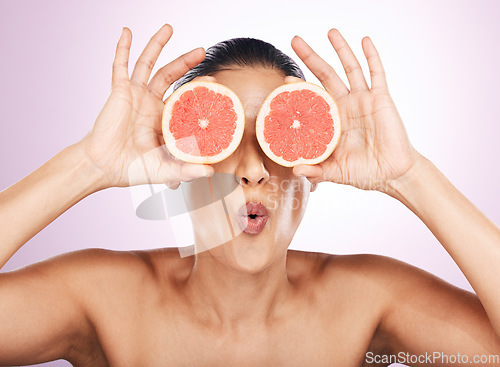 Image of Face kiss, grapefruit and skincare of woman in studio isolated on a purple background. Natural cosmetics, food and female model with fruit for vitamin c, nutrition or healthy diet, wellness or beauty