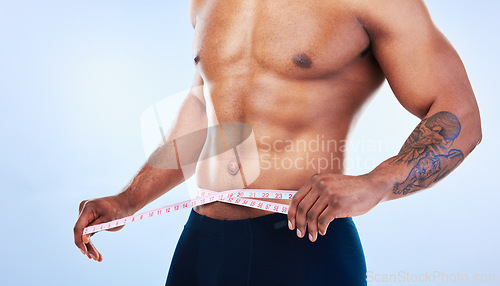 Image of Black man, fitness and body, measuring tape and abs with health, weight loss and active lifestyle on blue background. Shirtless male bodybuilder, exercise and wellness with diet, healthy and strong