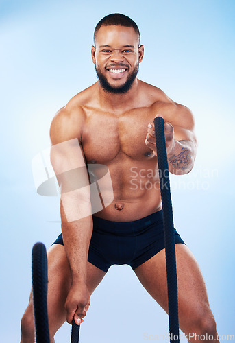 Image of Fitness, man and portrait in battle rope for intense workout, exercise or training against blue studio background. Strong and fit muscular male model in roping practice for exercising endurance