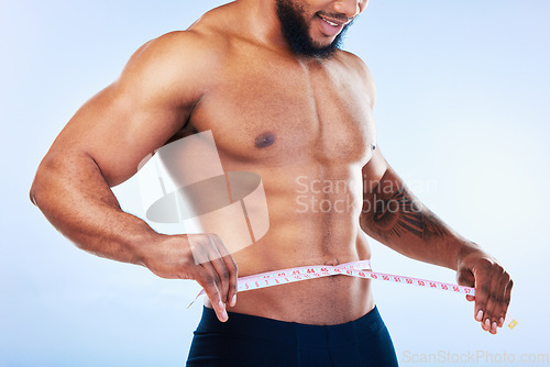 Image of Black man, exercise and body, weightloss and measuring tape with health and active lifestyle on blue background. Shirtless male bodybuilder, abs and fitness with diet, healthy and strong in studio