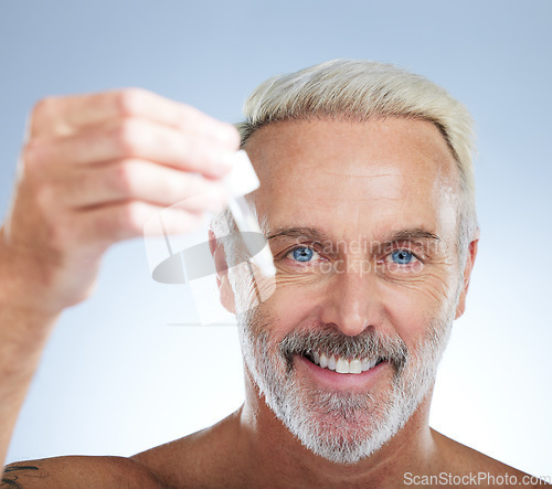 Image of Old man, portrait and smile, face with serum for skincare, beauty and grooming with facial oil on studio background. Closeup of dropper, anti aging cosmetic care with happy senior male and hygiene