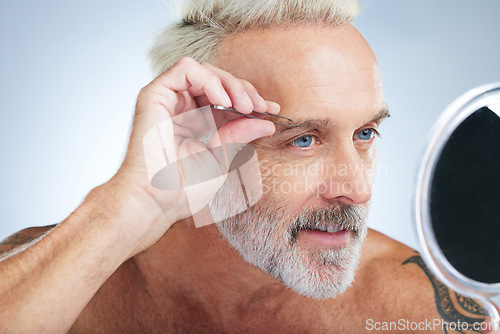 Image of Senior man, bathroom tweezers and mirror check in a studio doing hair removal and grooming. Wellness, eyebrows and beauty routine of a male model care with grey background and steel tools for face