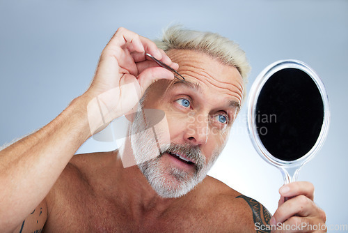 Image of Senior man, tweezers and eyebrow in studio with mirror, grooming and self care for beauty by background. Model, check and tweezing for facial hair removal, cleaning and elderly cosmetics by backdrop