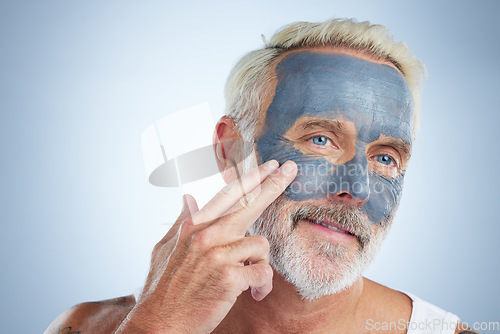 Image of Elderly man, skin and face mask in studio for health, wellness and organic cleaning with smile by background. Senior model, hand or natural charcoal product for facial cosmetics for dermatology detox