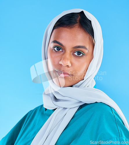 Image of Muslim, serious woman and portrait with scarf on blue background, studio and backdrop. Young female model, islamic culture and beauty of empowerment, proud religion or arabic fashion of elegant hijab