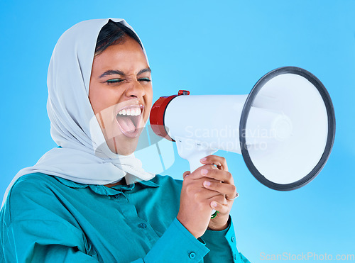 Image of Young woman, muslim and loudspeaker in studio for protest, human rights and scream by blue background. Girl, islam and megaphone for speech, justice and vote for freedom, mission and power politics