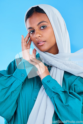 Image of Muslim, woman and serious portrait in studio, blue background and color backdrop. Young female model, islamic culture and beauty of empowerment, proud religion and arabic fashion of elegant hijab