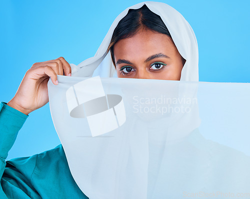 Image of Muslim woman cover face with scarf in studio, blue background and color backdrop. Portrait, islamic female model and hijab for beauty, culture and confidence of religion, arabic fashion and style