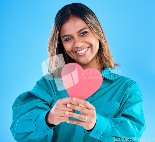 Image of Paper heart, happy woman and portrait in studio, blue background or backdrop. Smile, female model and shape of love, trust and support of peace, thank you and kindness on valentines day, date or hope