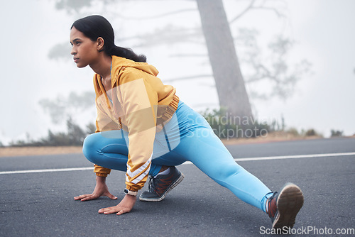 Image of Outdoor fitness leg stretching, woman and runner exercise on a road in the mountains with focus. Workout warm up, running training and wellness of a young female ready for sports and marathon run