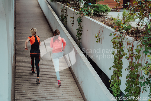 Image of Two women in sports clothes running in a modern urban environment. The concept of a sporty and healthy lifestyle